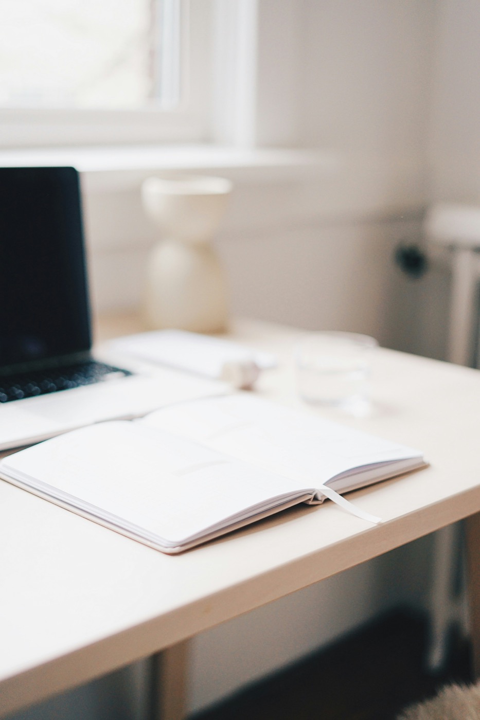 A bright desk with a laptop and an open journal